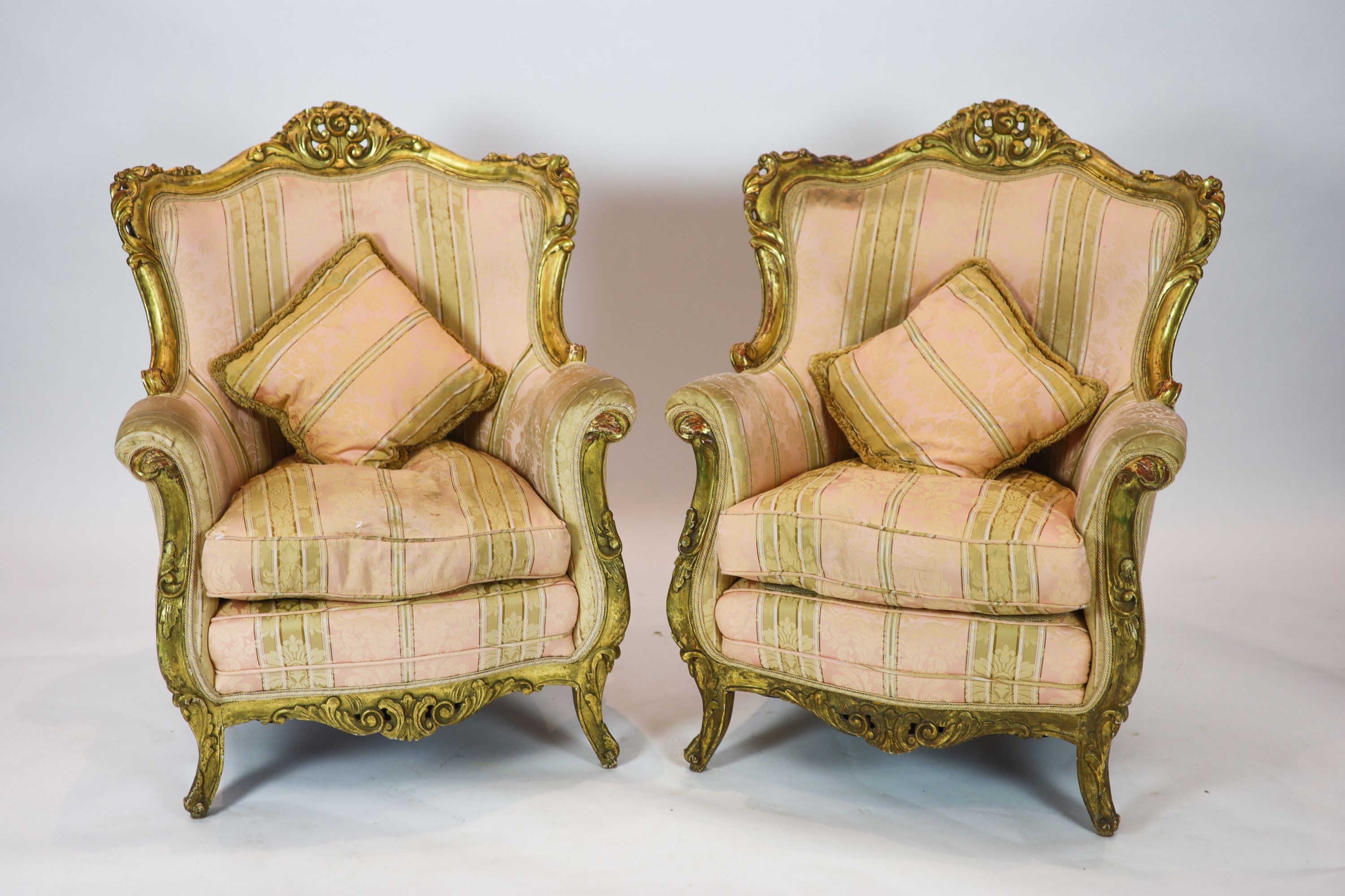 A Louis XV style carved gilt wood five piece suite, consisting of a three seater settee and four fauteuils, all with scroll carved backs and arms, on short cabriole legs